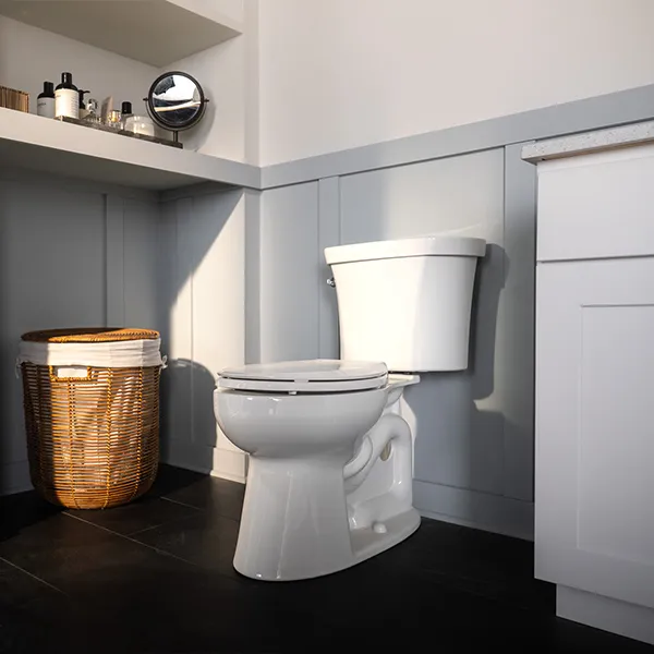 White modern toilet with closed lid in a bathroom with gray panel walls and black floor tiles.
