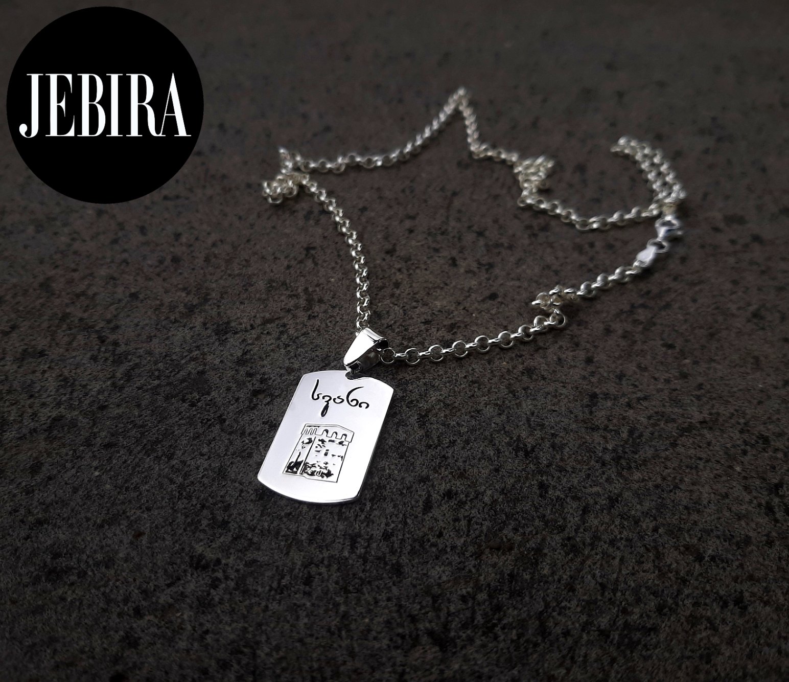 ვერცხლის კულონი მართკუთხა ფორმის გრავირებით სვანური კოშკის გამოსახულებით და წარწერით ქვედა მხარეს "სვანი"