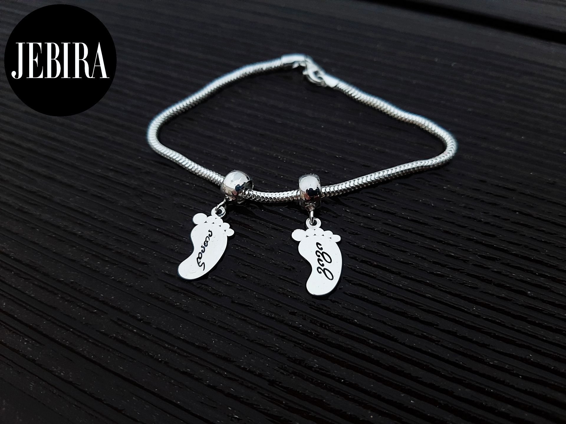 ვერცხლის სამკაული, ვერცხლის სამაჯური პატარა ბავშვის ფეხებით რომელზეც გრავირება არის გაკეთული კერძოდ სახელები