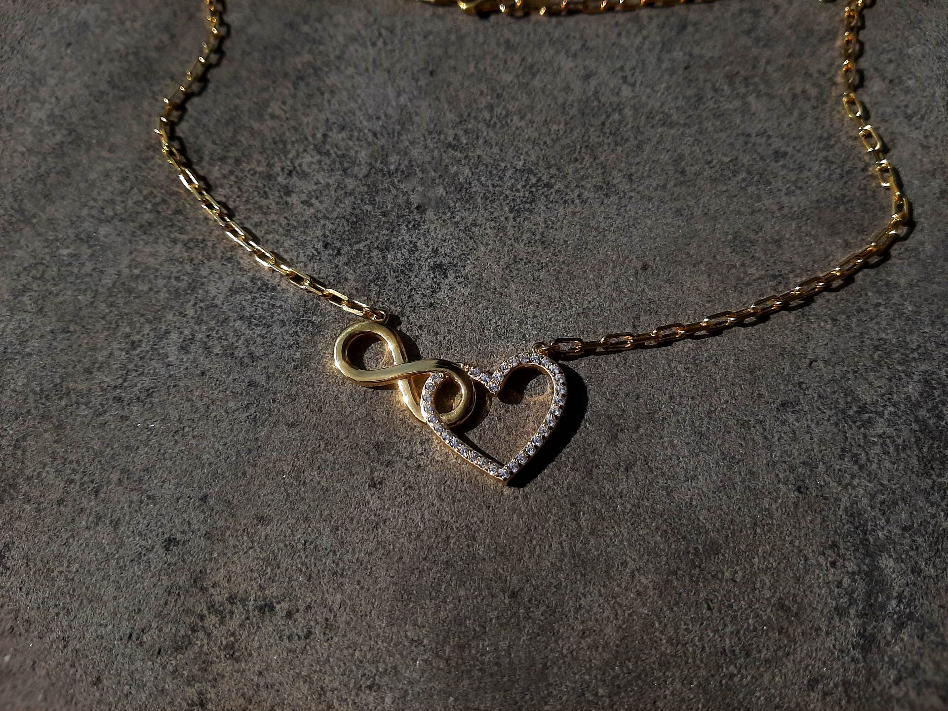 ვერცხლის ყელსაბამი მოოქროვილი უსასრულობის და გულის გამოსახულებით , რომელშიც ჯდება ცირკონის თეთრი თვლები გარშემო