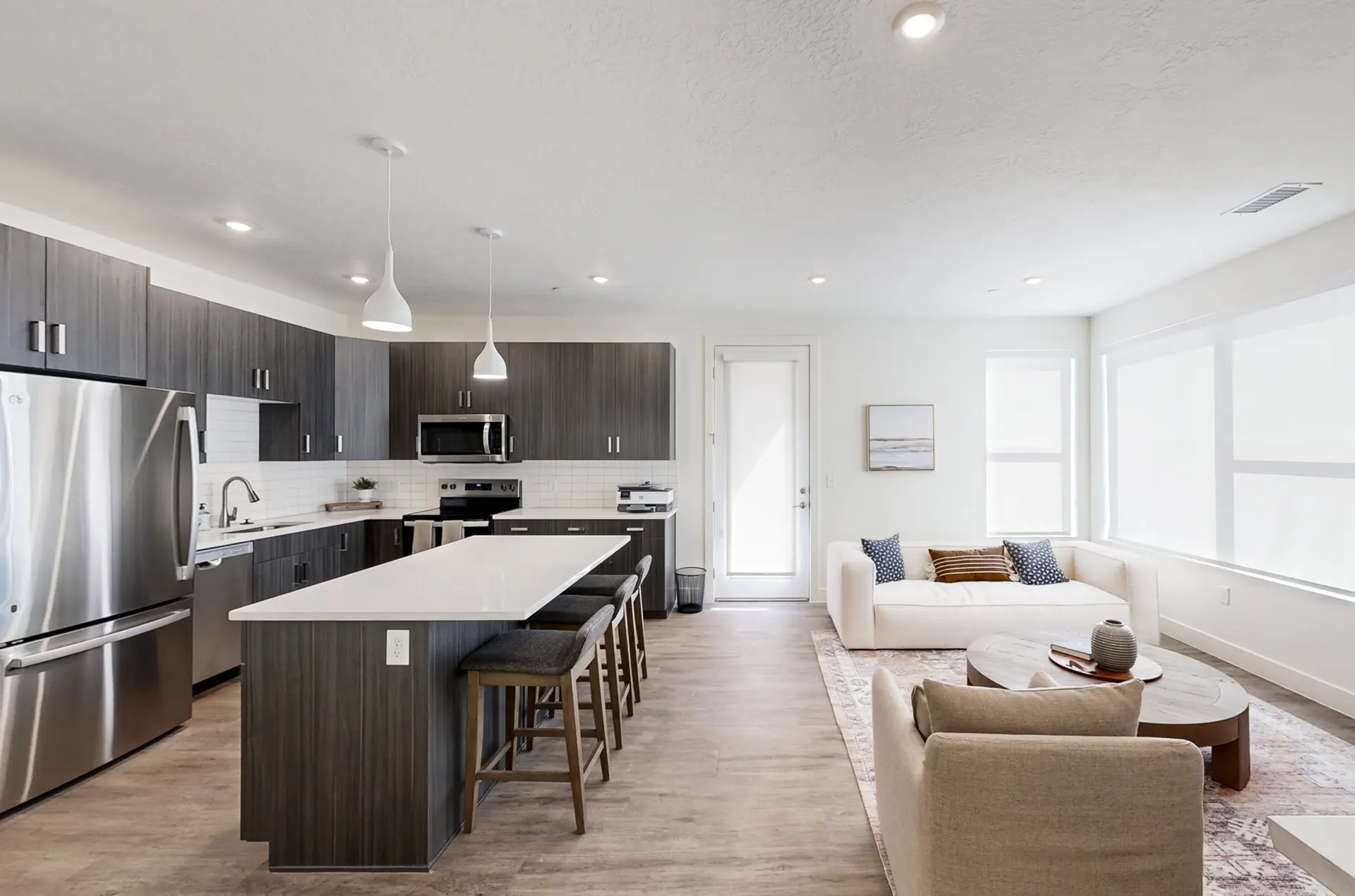 Bright open-concept kitchen and living room at Valora Apartments featuring modern cabinetry, large island, and spacious natural-light windows.