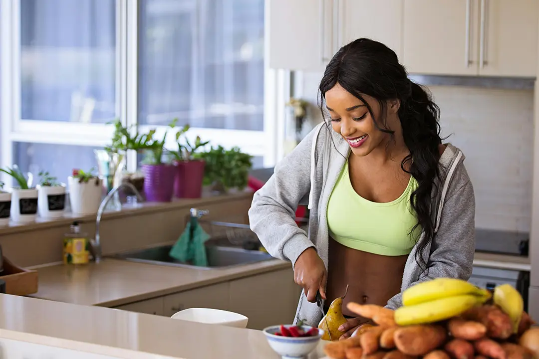 Young woman preparing fresh food in a bright, modern kitchen, enjoying a healthy lifestyle at home.