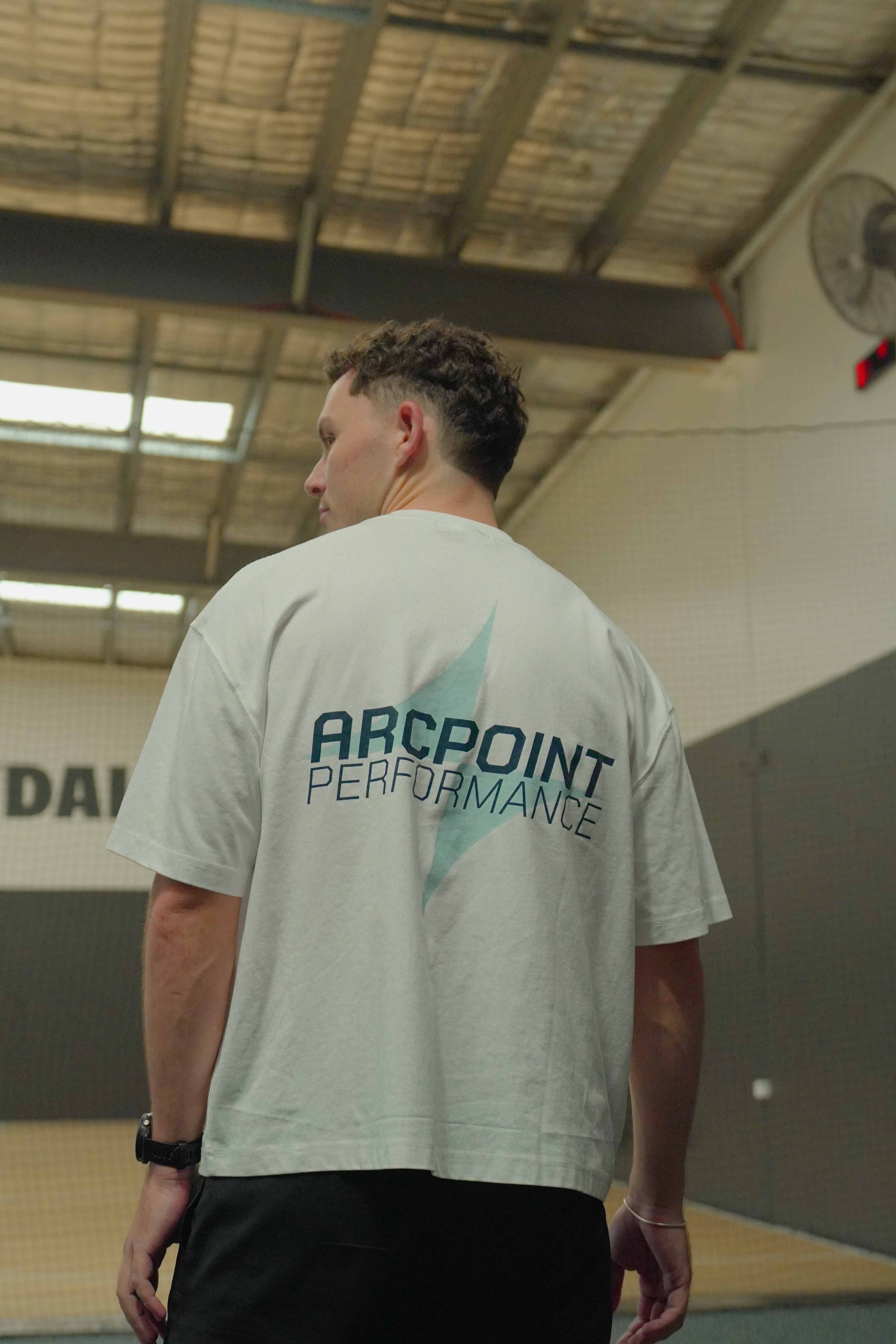 Person wearing a white sleeveless athletic tank top with a small logo on the left chest and initials 'AP' on the right chest.