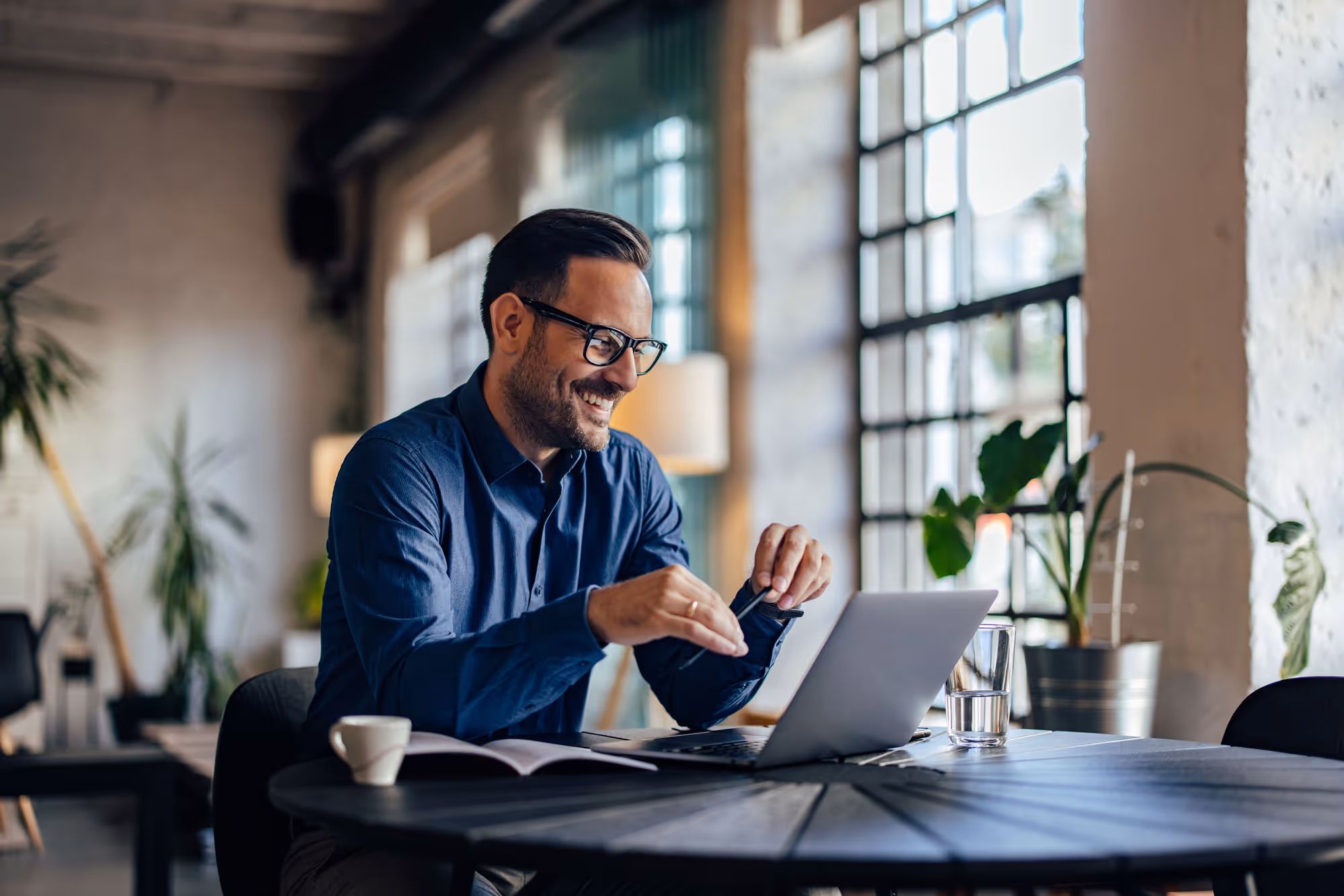 Business professional working on laptop in bright modern office with plants