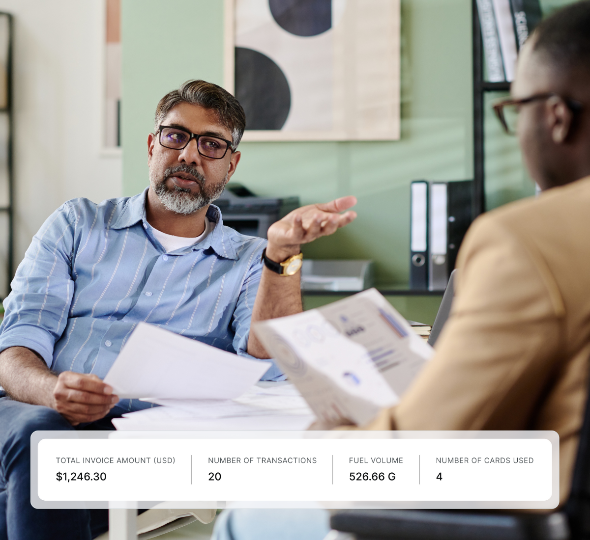Two men having a discussion in an office, one holding documents and gesturing, with an overlay showing Total Invoice Amount $1,246.30, Number of Transactions 20, Fuel Volume 526.66 G, and Number of Cards Used 4.