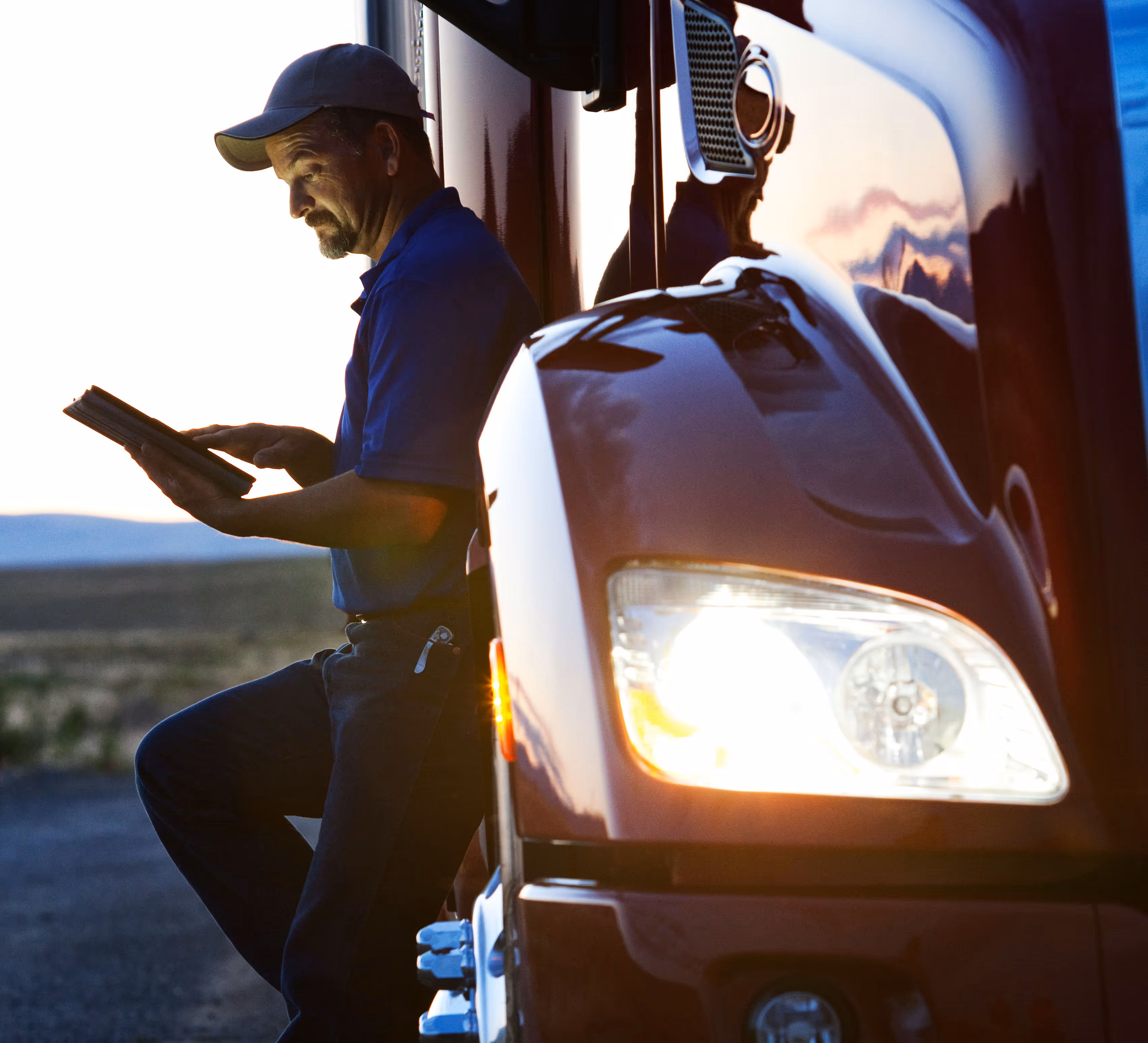 Two people sitting at a table looking at a laptop, one person pointing at the screen.