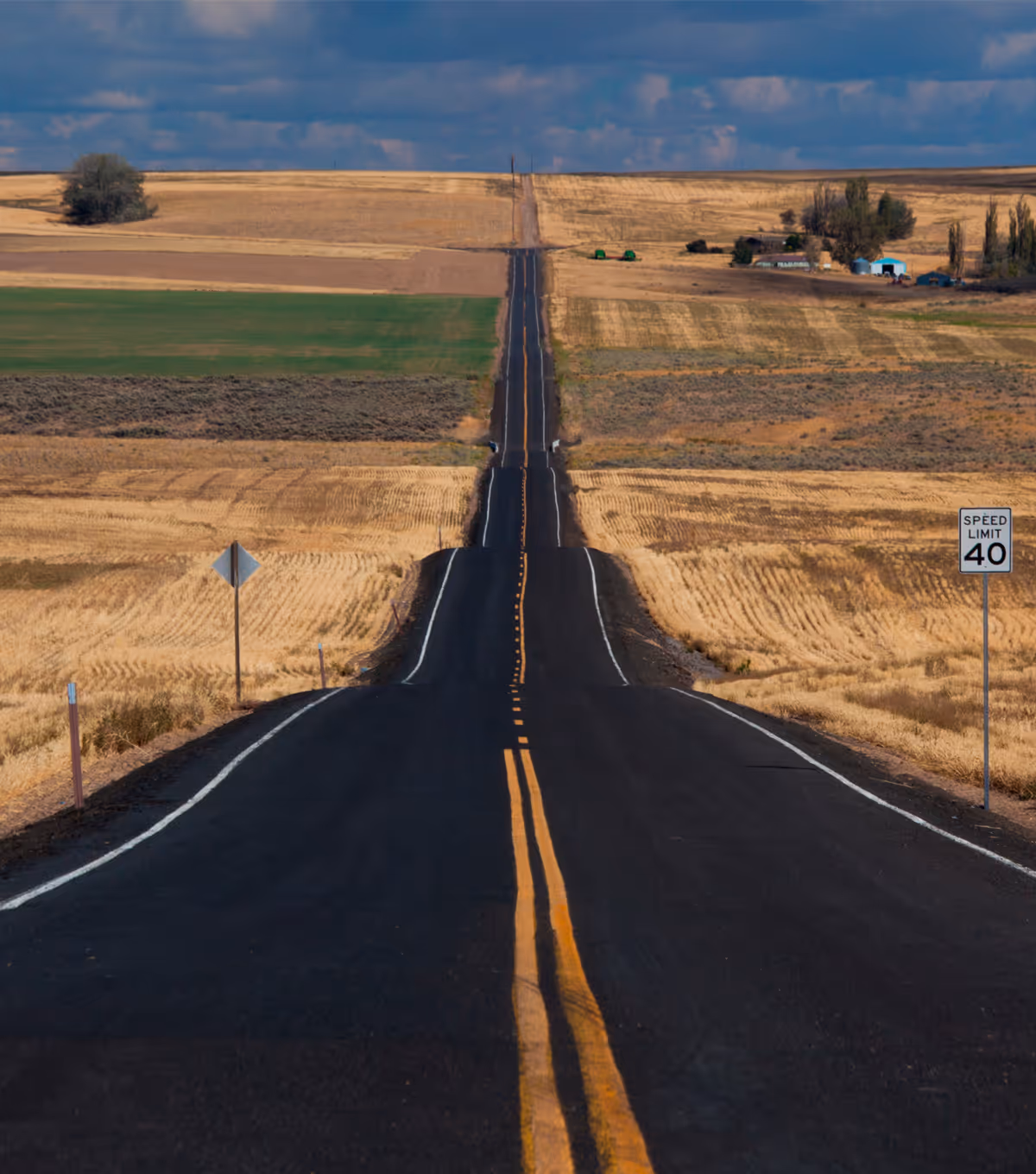 Two people sitting at a table looking at a laptop, one person pointing at the screen.