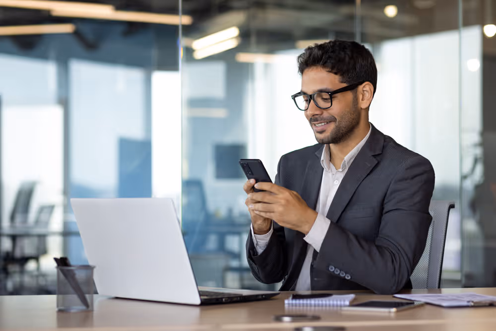 Man with glasses and beard smiling while looking at his smartphone, with an overlay chart showing vendor usage by volume for November 2025.