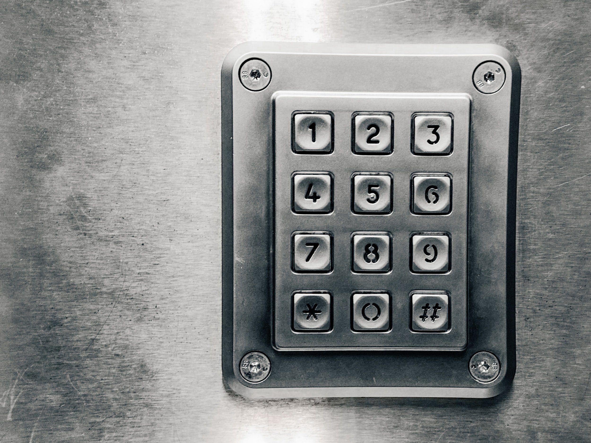 Metal keypad with numbers 1 to 9 and symbols *, 0, and ## in a 4x3 layout mounted on a brushed metal surface.
