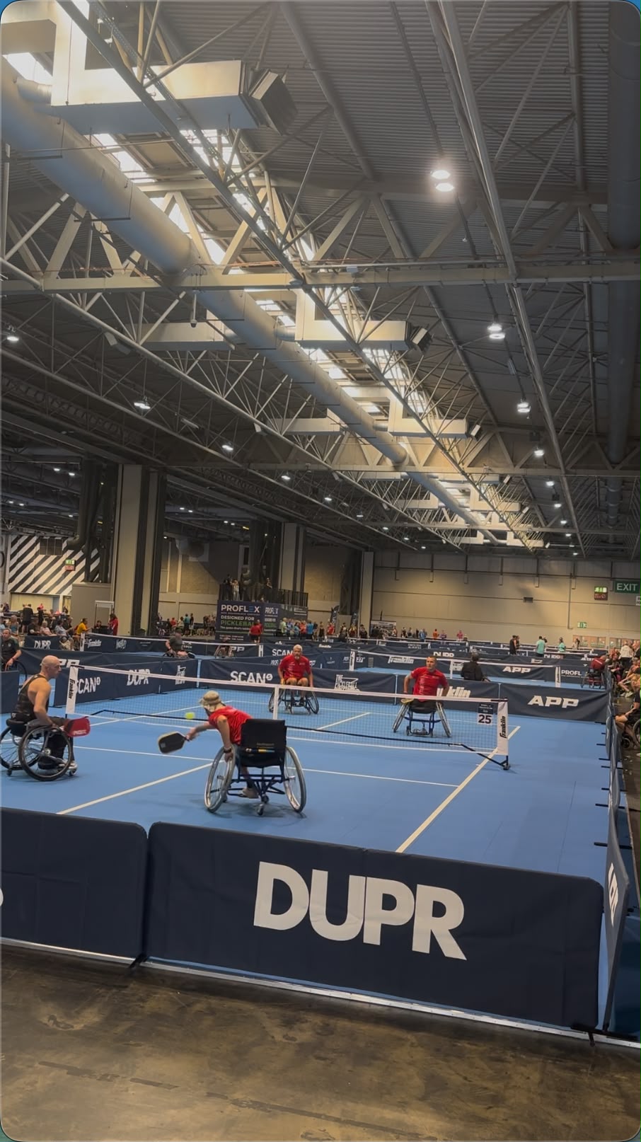 Wheelchair pickleball players competing in doubles on indoor pickleball courts.