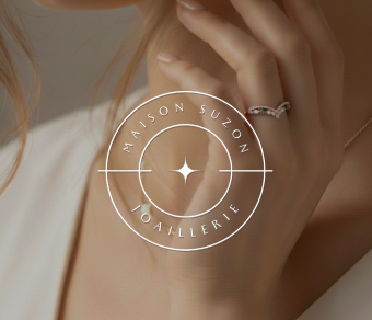 Main féminine portant une bague élégante avec des pierres précieuses, en arrière-plan flou et logo Maison Suzon Joaillerie.