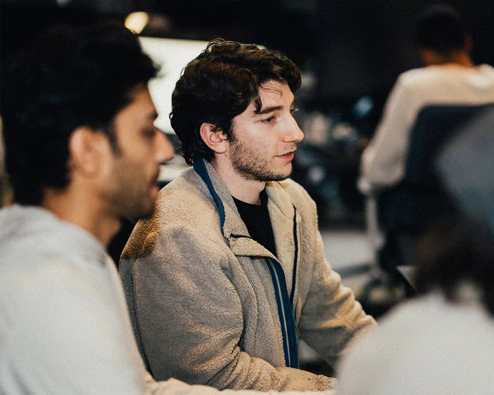 Two men seated and engaged in a conversation or discussion in an indoor setting.