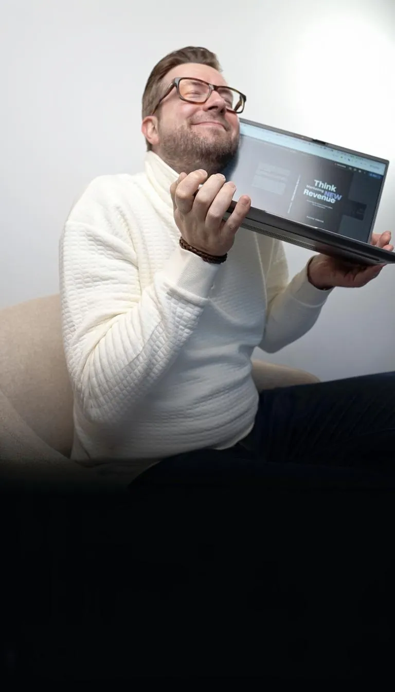 Sascha Albrink, der einen Laptop dicht vor seinem Gesicht hält und auf einem beigen Stuhl sitzt.