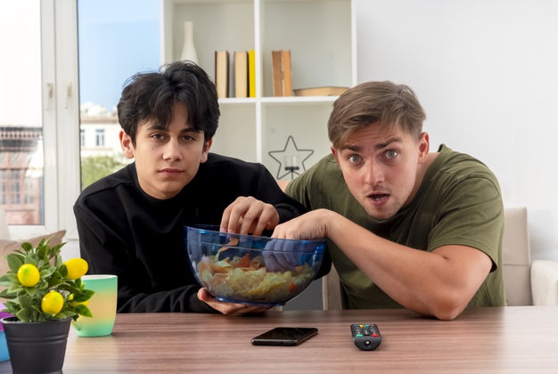 guys-siting-on-table-holding-eating-bowl-chips