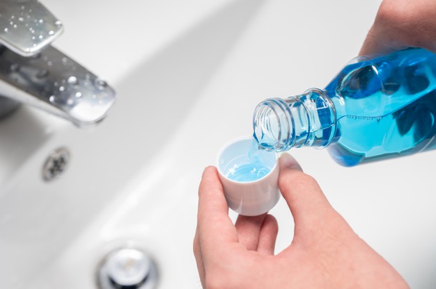 hand-man-pouring-bottle-mouthwash-into-cap-dental-blog-mouthwash