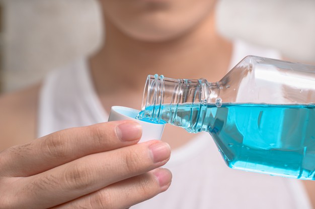 hand-man-pouring-bottle-mouthwash-into-cap-time-to-use-mouthwash
