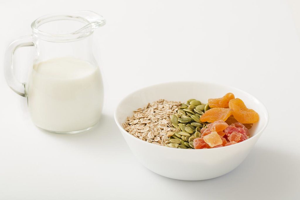 milk-with-healthy-bowl-muesli-pumpkin-seeds-dry-fruits-white-bowl-white-background-eat-healthy-dental-blog-dental-dost