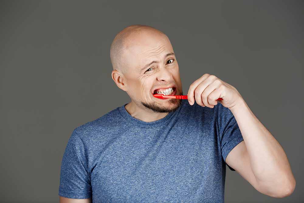 portrait-handsome-man-grey-shirt-brushing-teeth-dark-wall-gum-problem-dental-blog-dental-dost