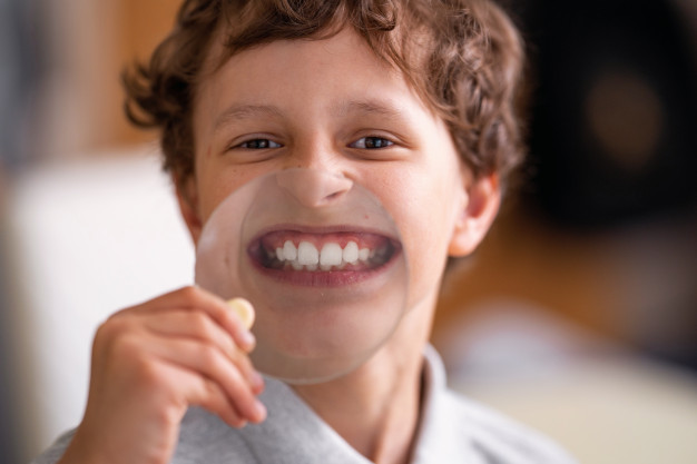 cheerful-child-with-glasses-shows-white-teeth-glass-large-magnifying-glass-dental-fluorosis-dental-blog