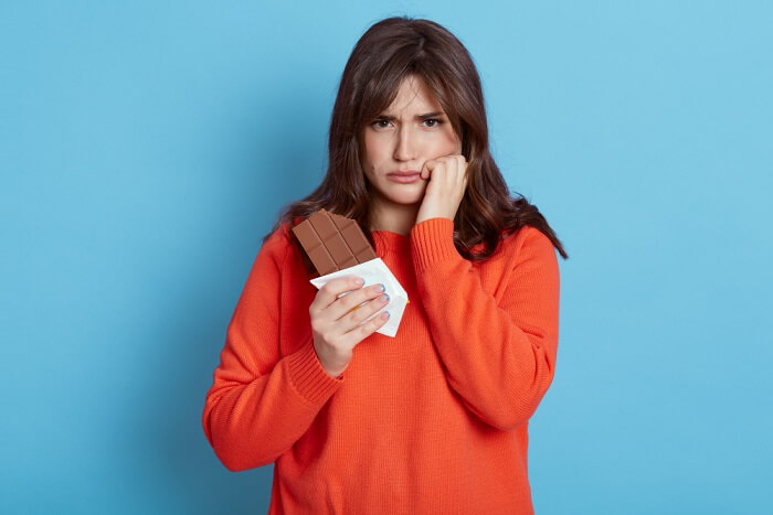woman toothache standing with chocolate in hand