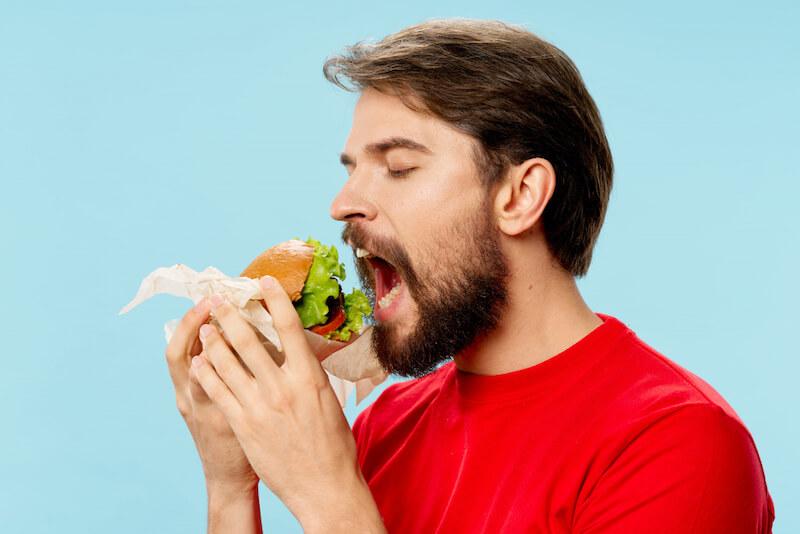 young-man-with-juicy-hamburger-his-hands-man-eating-burger