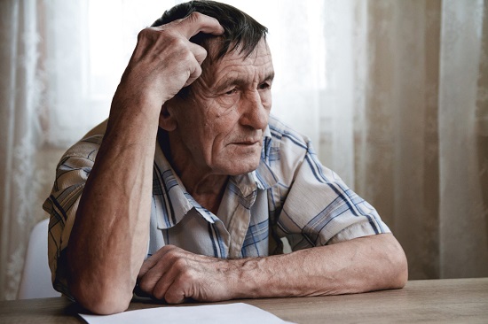 elderly-man-sits-holding-his-head-suffering-from-memory-loss