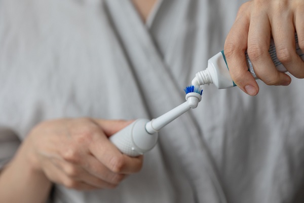 woman-brushing-her-teeth-with-electric-toothbrush-oral-dental-care-human-personal