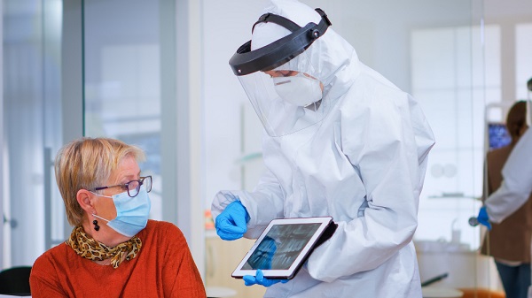 woman-sitting-chair-waiting-area-with-protection-mask-listening-doctor-with-overall-looking-tablet-clinic-with-new-normal-assistant-explaining-dental-problem-during-coronavirus-pandemic