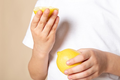 close-up-view-boy-holding-lemon-slice-for-teeth-whitening