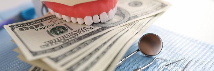 dental-artificial-jaw-instrument-one-hundred-dollar-bills-dentist-desk-dental-treatment-costs