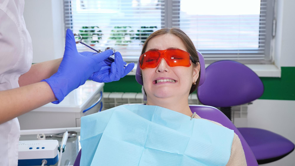 woman-afraid-remove-tooth-sitting-dental-chair-while-doctor-stands-patient-holding-syringe-hands