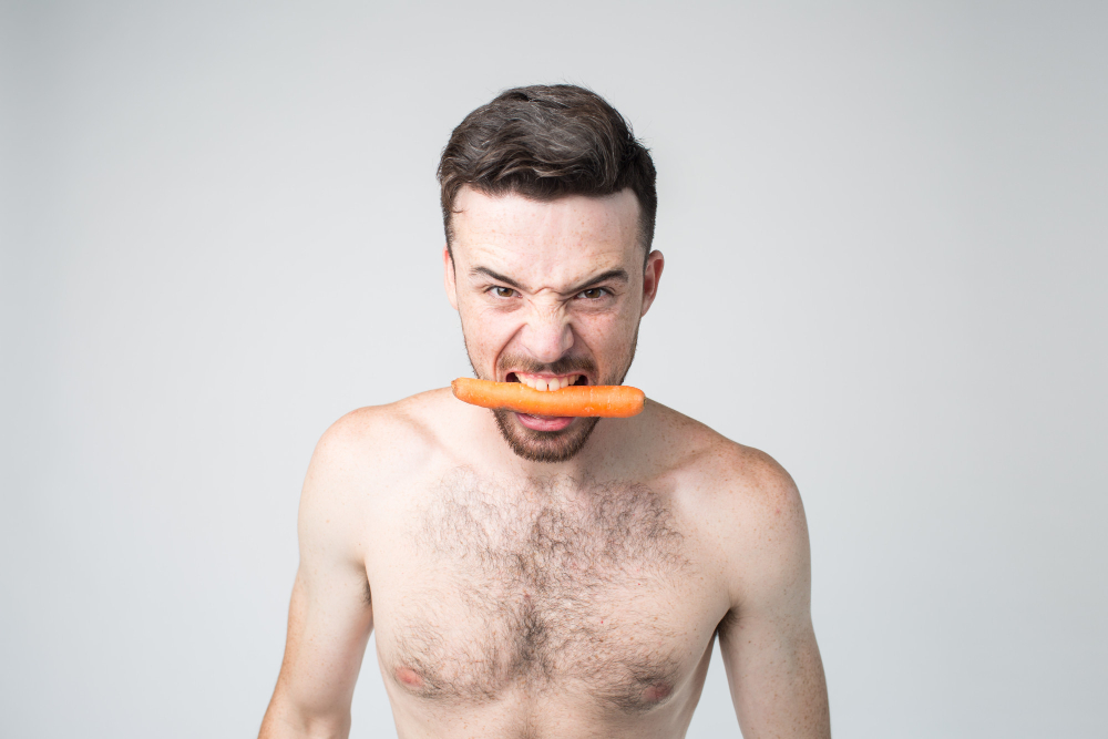 young-man-hold-carrot-teeth-showing-Food-begins-to-rot-between-teeth