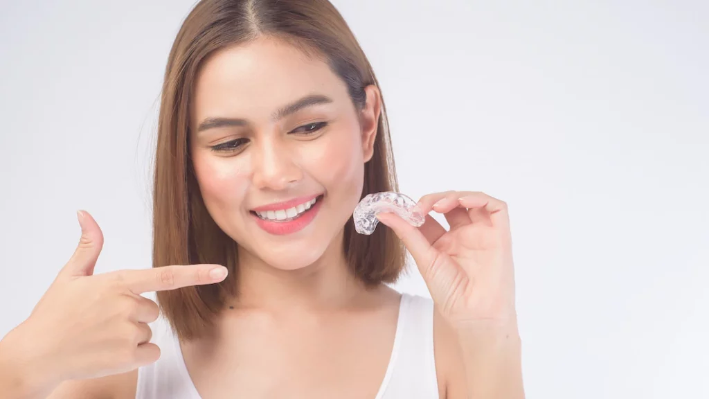 young-smiling-woman-holding-clear-aligners