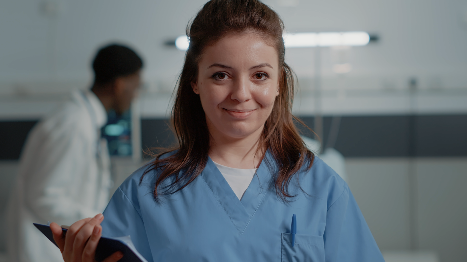 To personer sitter på en moderne, buet benk i et profesjonelt kontormiljø og samtaler. Den ene holder et nettbrett.