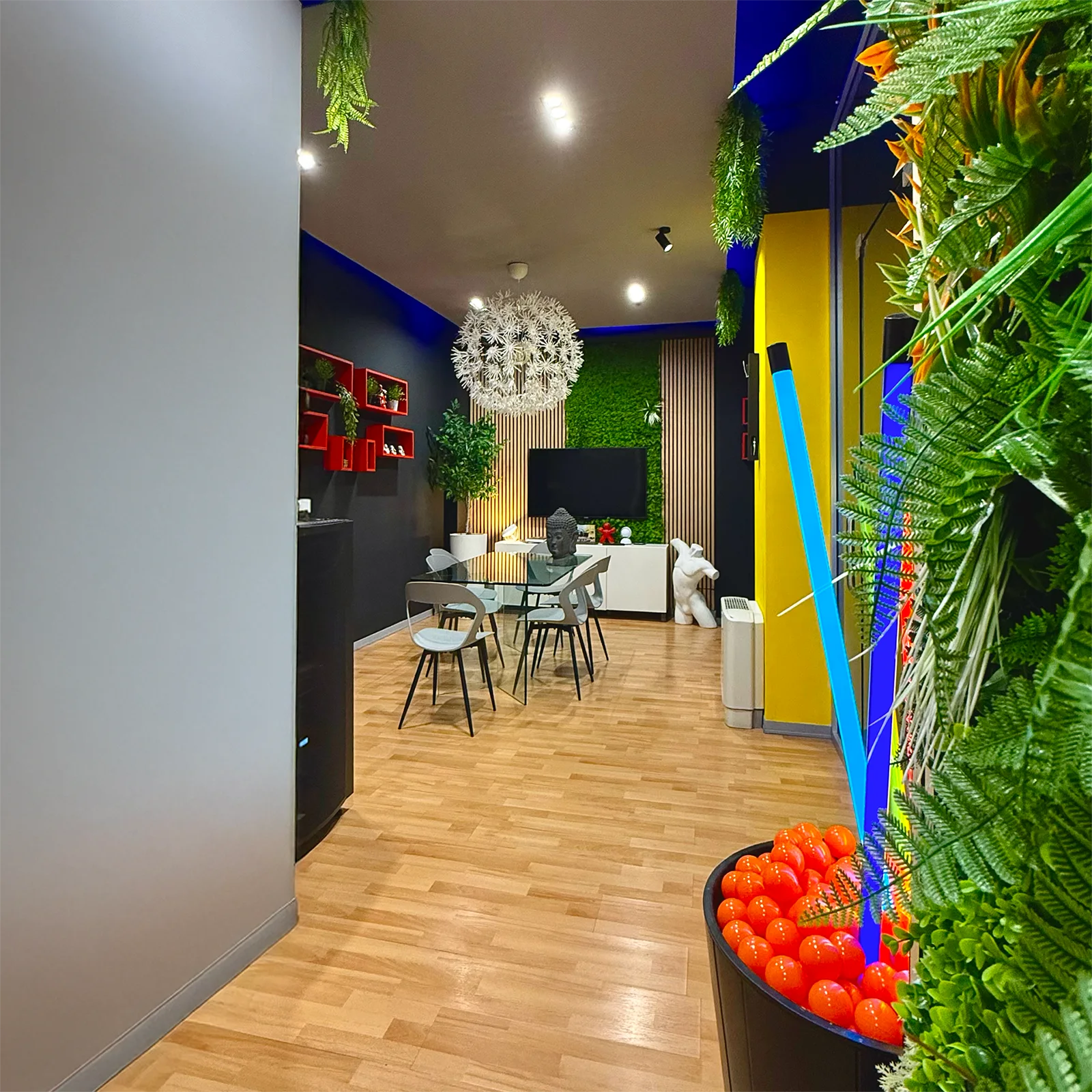 Scatto degli interni dello studio Digistart: ambiente moderno e colorato con pareti verde verticale, arredi di design, luci LED e dettagli decorativi vivaci. Uno spazio creativo pensato per brainstorming, riunioni e produzione di contenuti, cuore operativo di Digistart, agenzia creativa a Torino.