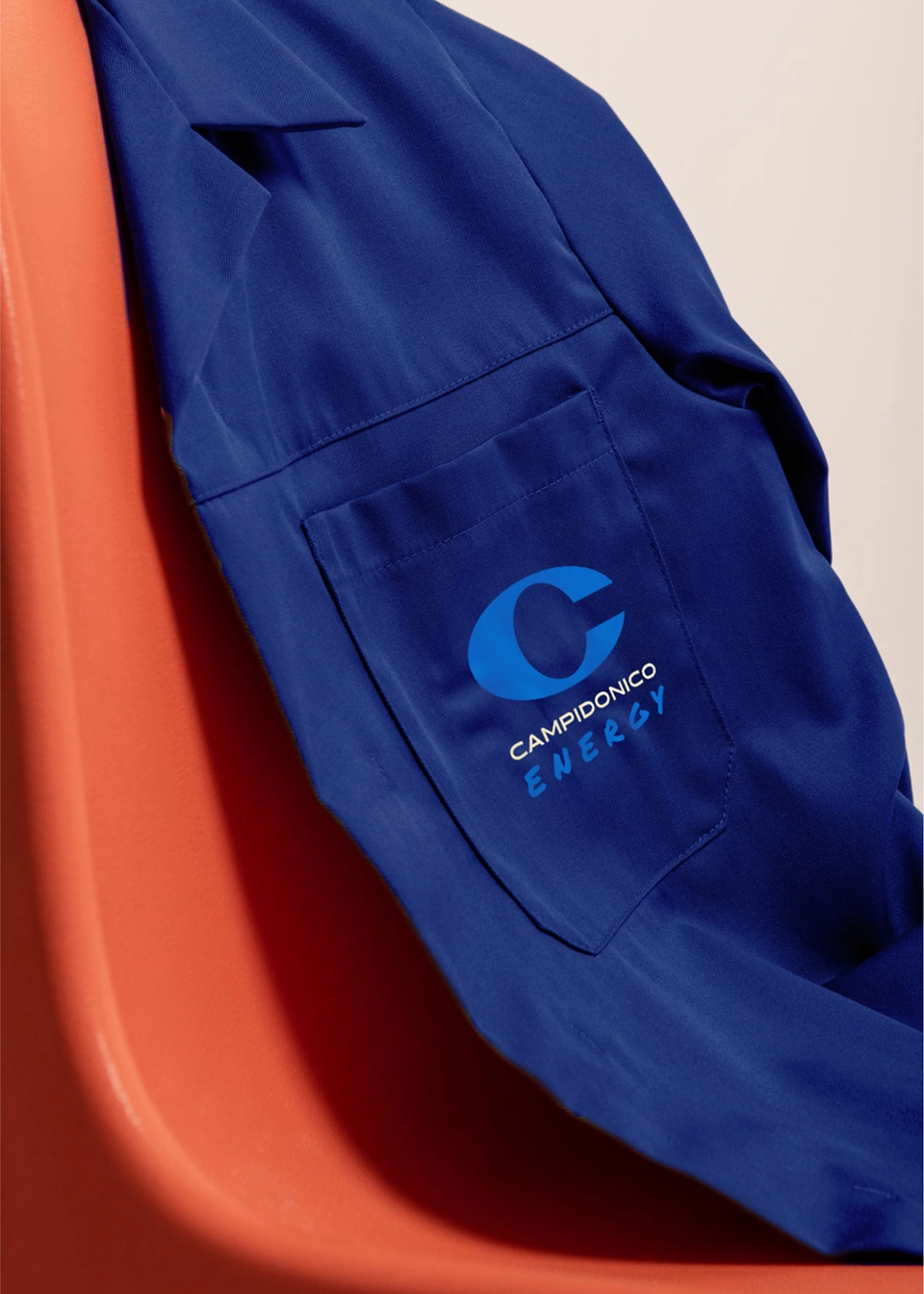 Giacca blu blu con logo Campidonico Energy su fondo arancione, parte del merchandising e dei materiali fisici creati da Digistart per aumentare visibilità e riconoscibilità del brand.