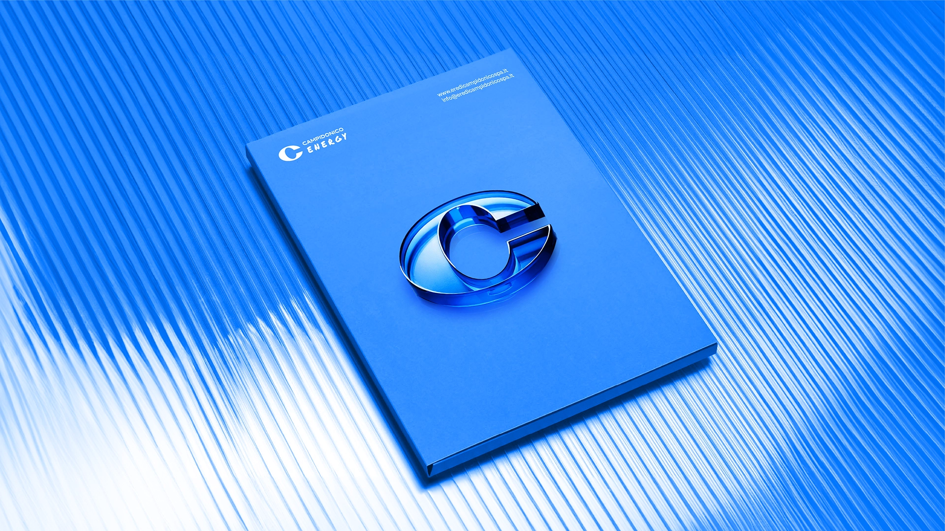 Elemento di brand per Campidonico Energy: cartellina blu con simbolo tridimensionale ispirato al logo, rappresentazione visiva dell’energia come forma fluida e continua, design Digistart.