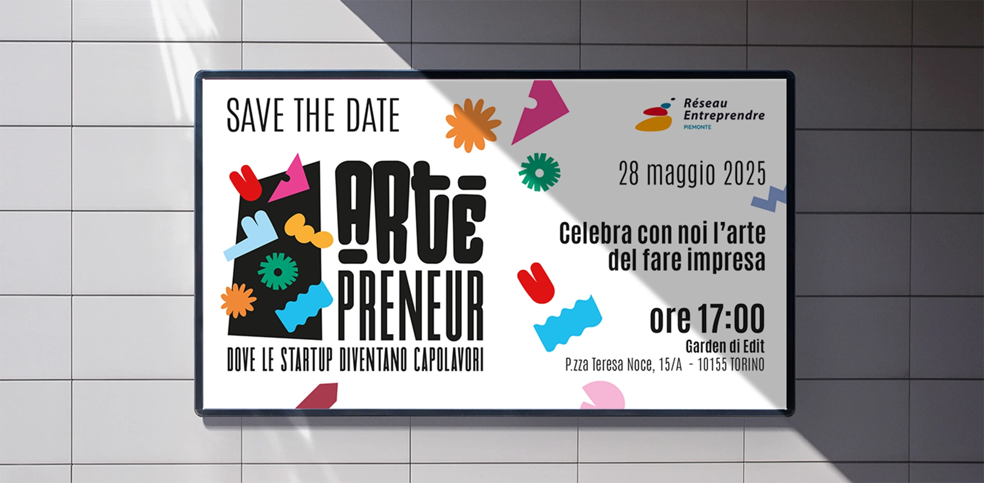 Save the date per l’evento Artepreneur di Réseau Entreprendre Piemonte: poster affisso su parete con data, payoff “Celebra con noi l’arte del fare impresa” e grafica colorata coordinata, design curato da Digistart.