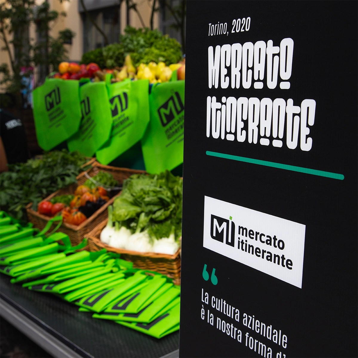 Totem espositivo per iniziativa collegata ad Artepreneur: struttura verticale “mercato itinerante” posizionata tra le cassette di verdura, esempio di applicazione del linguaggio visivo dell’evento in contesti reali, progettato da Digistart.