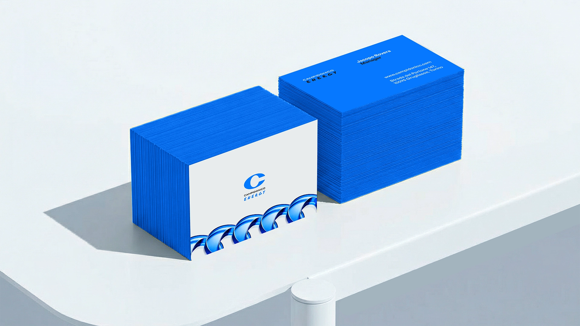 Materiali di brand identity per Campidonico Energy: biglietto da visita appoggiato su una grande C blu, progettati da Digistart per dare coerenza a tutta la comunicazione.
