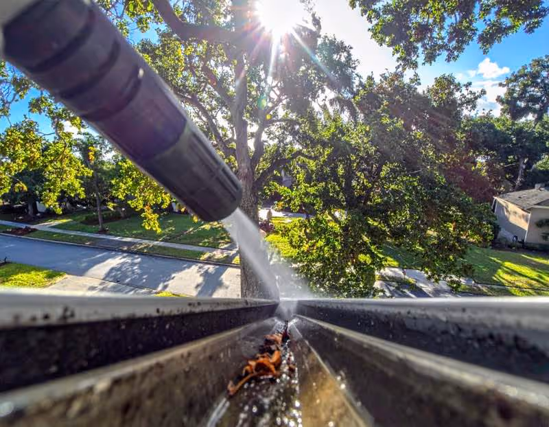 A gutter on a home in Orlando being cleaned by a pressure washer stream of water
