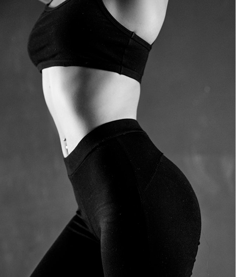 Side view of a person in black workout clothes showing toned waist and hips.