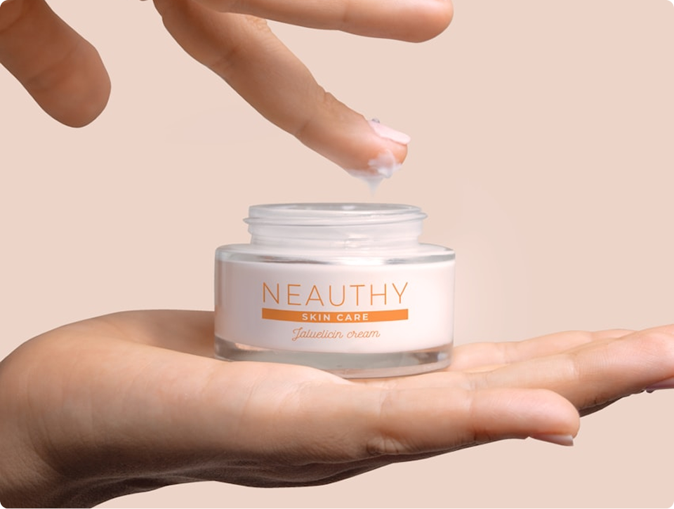 Hand holding a jar of Neauthy skin care Jatuleicin cream with a finger dipping cream from the jar.