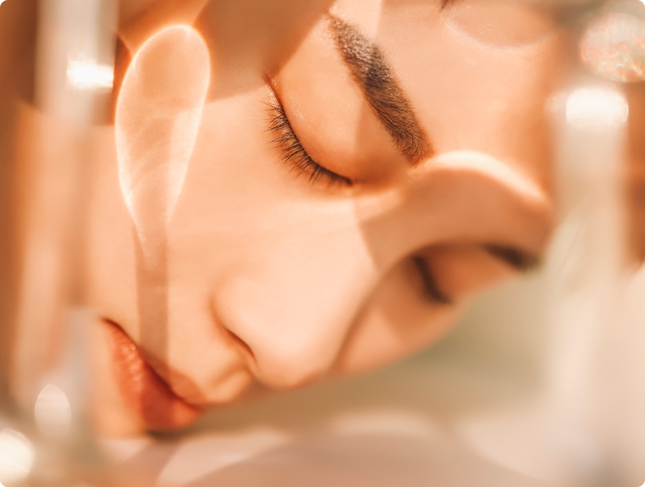 Close-up of a serene person with closed eyes and soft lighting creating warm reflections on their face.