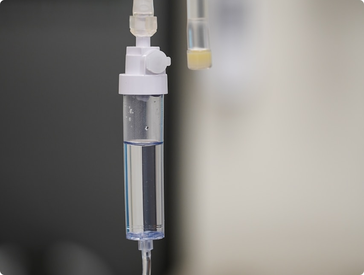 Close-up of a clear intravenous drip chamber with fluid inside, used for medical IV therapy.