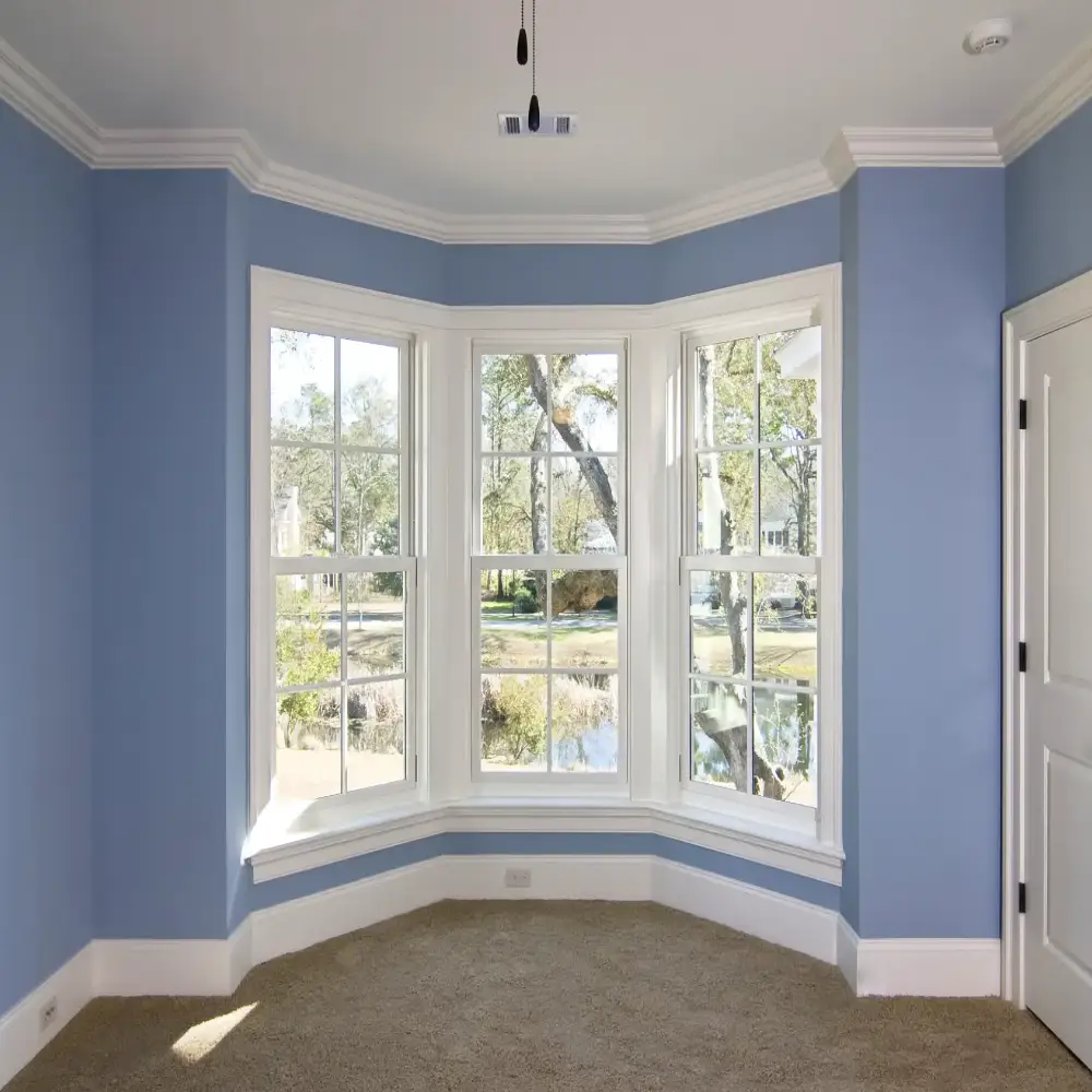 Bright bedroom with blue walls and large windows showcasing natural sunlight and interior design
