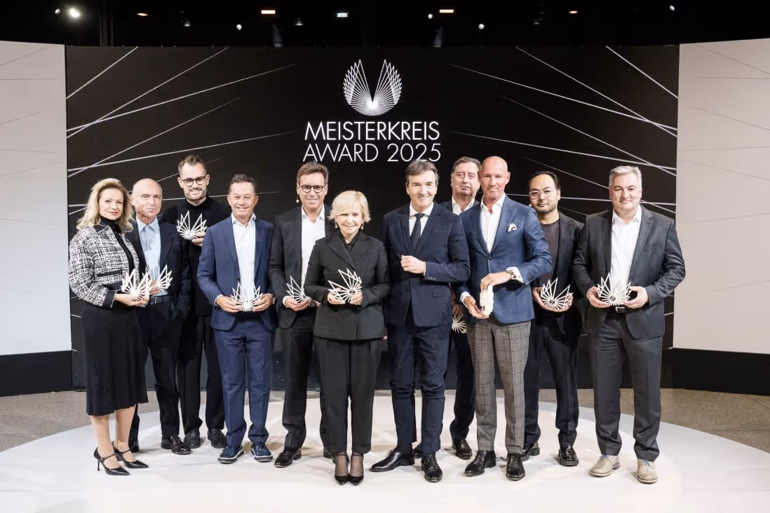 Group of eleven people dressed formally holding Meisterkreis Award trophies on a stage with a black backdrop reading 'MEISTERKREIS AWARD 2025'.