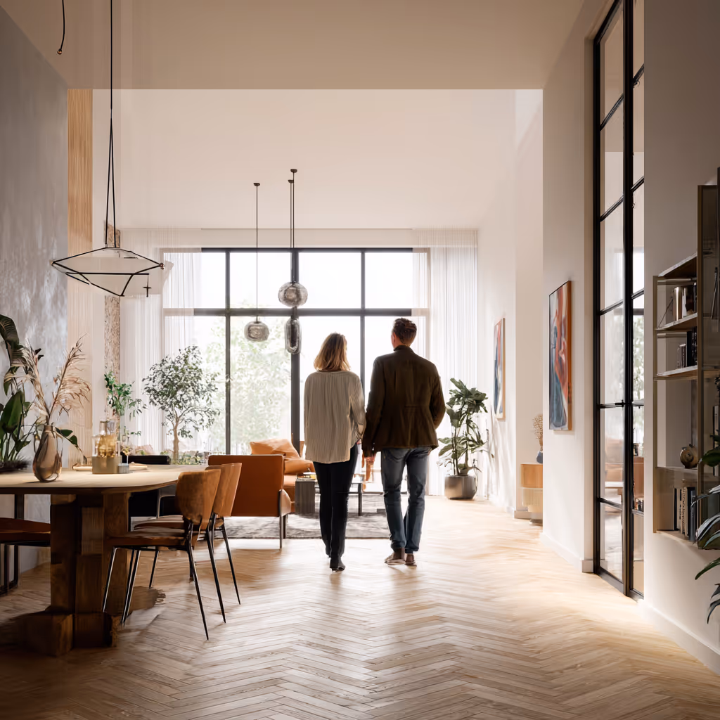 Een stel dat hand in hand loopt in een licht en ruim modern huis met houten vloer en grote ramen.
