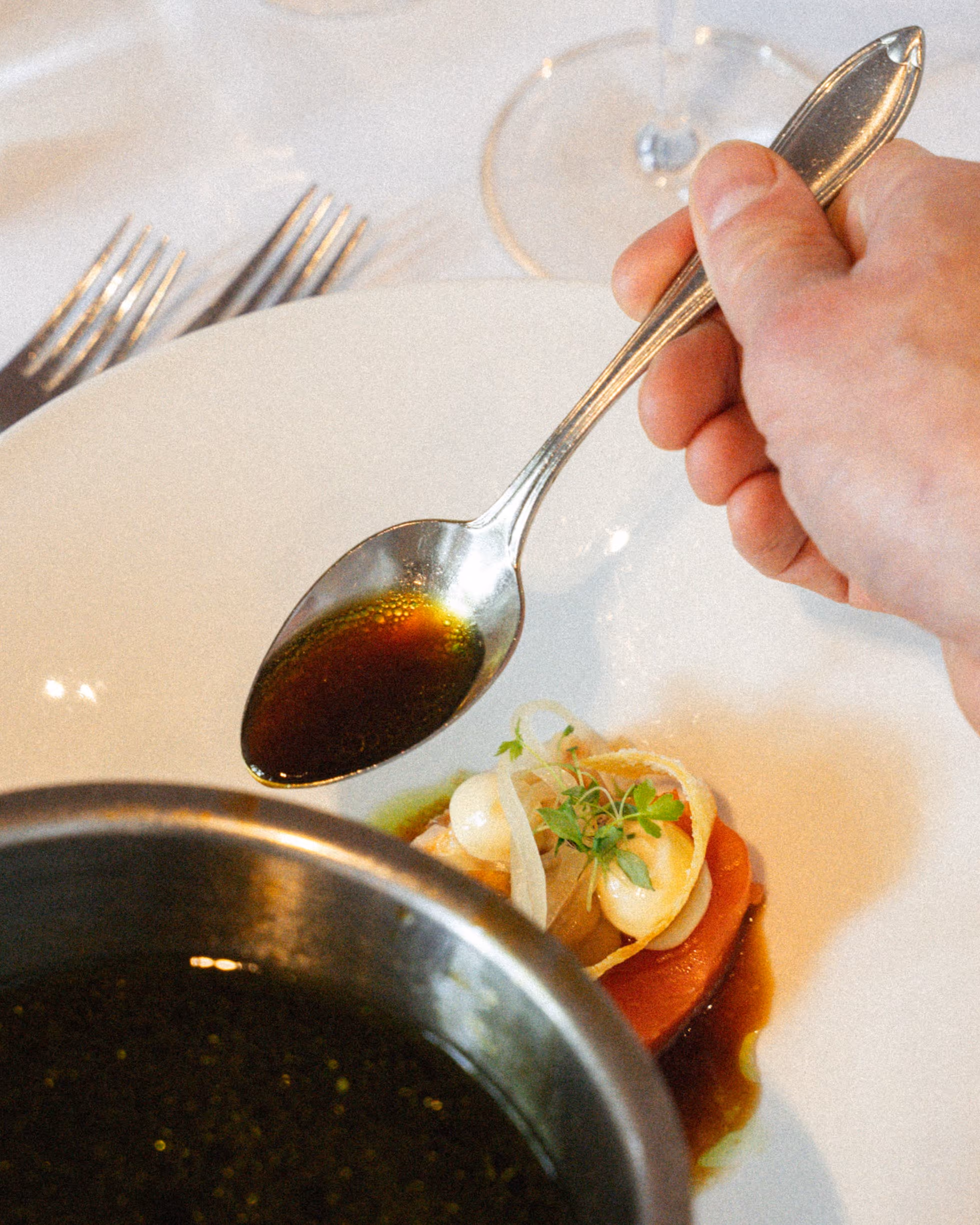 Nahaufnahme einer Vorspeise an welcher gerade aus einem Topf Sauce angegossen wird