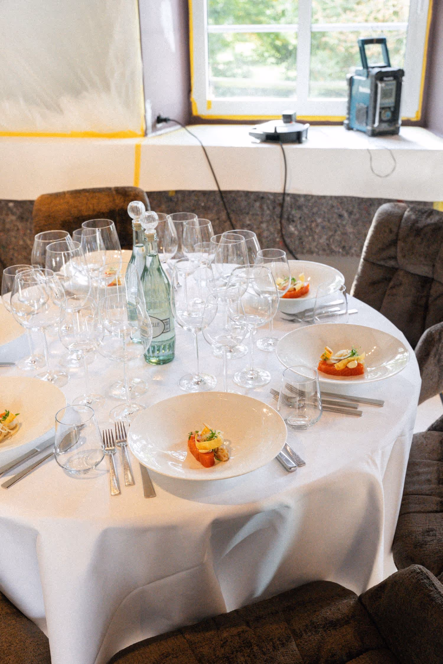 Tisch im Restaurant mit Gläsern, Wasserflasche, Teller mit einer Vorspeise